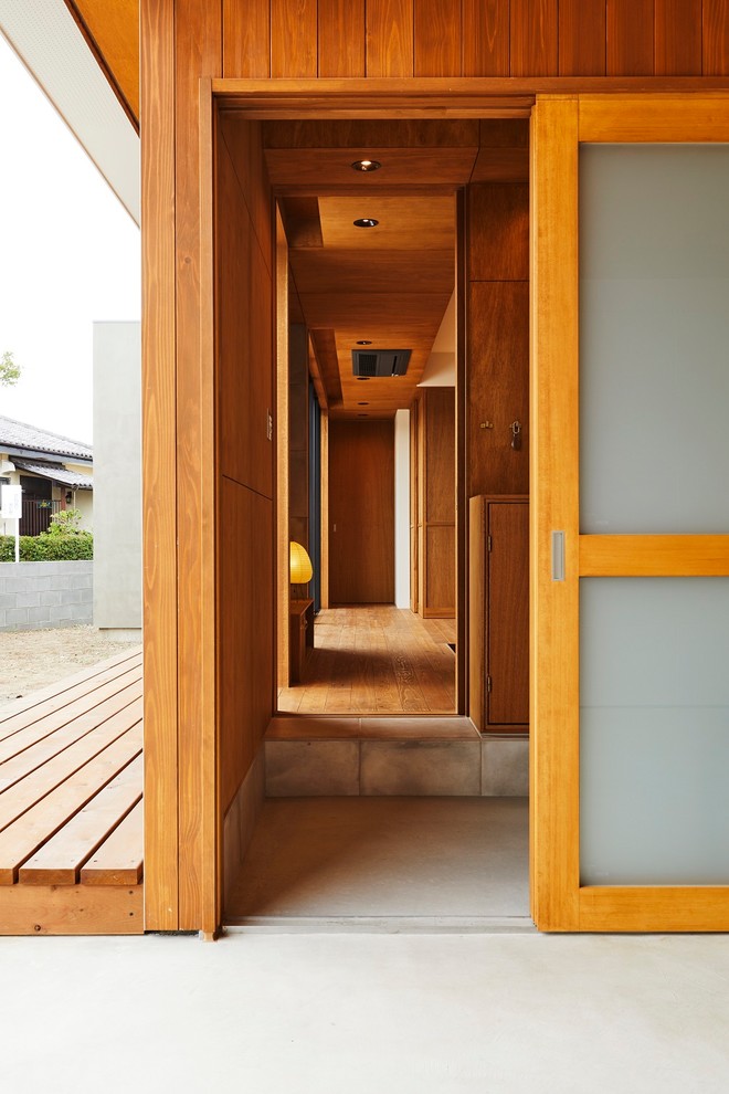 This is an example of a medium sized modern hallway in Other with brown walls, porcelain flooring, a sliding front door, a brown front door and beige floors.