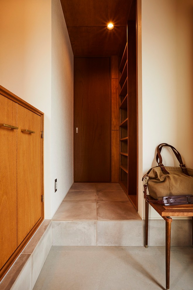 На фото: узкая прихожая среднего размера в стиле модернизм с коричневыми стенами, полом из керамогранита, раздвижной входной дверью, коричневой входной дверью и бежевым полом