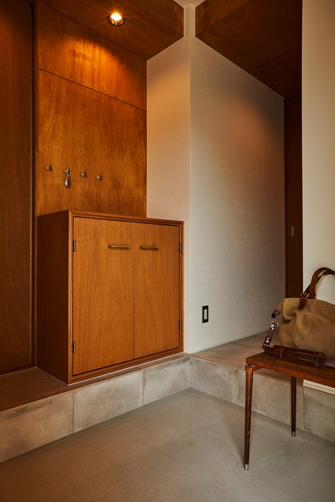 Ejemplo de hall moderno de tamaño medio con paredes marrones, suelo de baldosas de porcelana, puerta corredera, puerta marrón y suelo beige