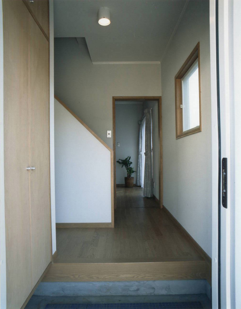 Foto på en entré, med vita väggar, plywoodgolv, en enkeldörr, en vit dörr och brunt golv