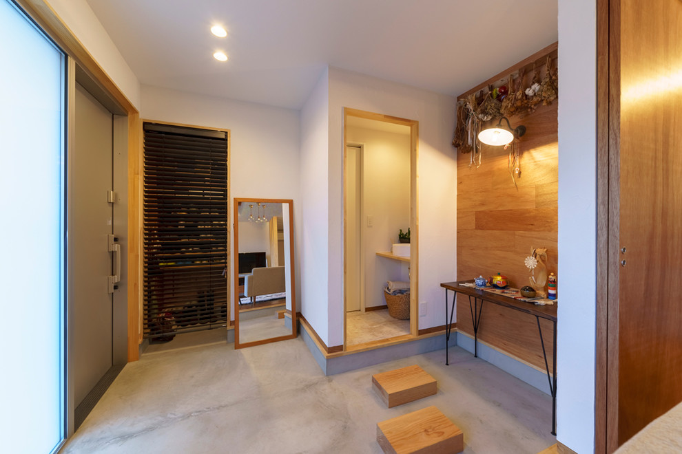 Kleiner Asiatischer Eingang mit braunem Boden, Korridor, weißer Wandfarbe, Betonboden, Schiebetür und Haustür aus Metall in Sonstige