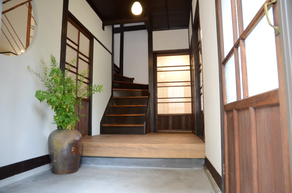 Réalisation d'une petite entrée asiatique avec un couloir, un mur gris, un sol en bois brun, une porte coulissante, une porte marron et un sol marron.