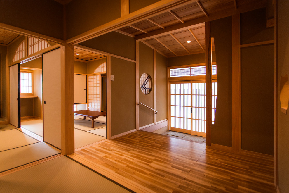 Ejemplo de entrada de estilo zen con paredes marrones, suelo de granito, puerta corredera y suelo gris
