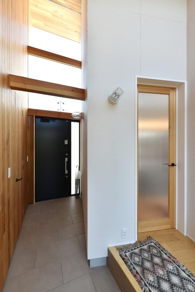 他の地域にあるアジアンスタイルのおしゃれな玄関 (白い壁、黒いドア、グレーの床) の写真