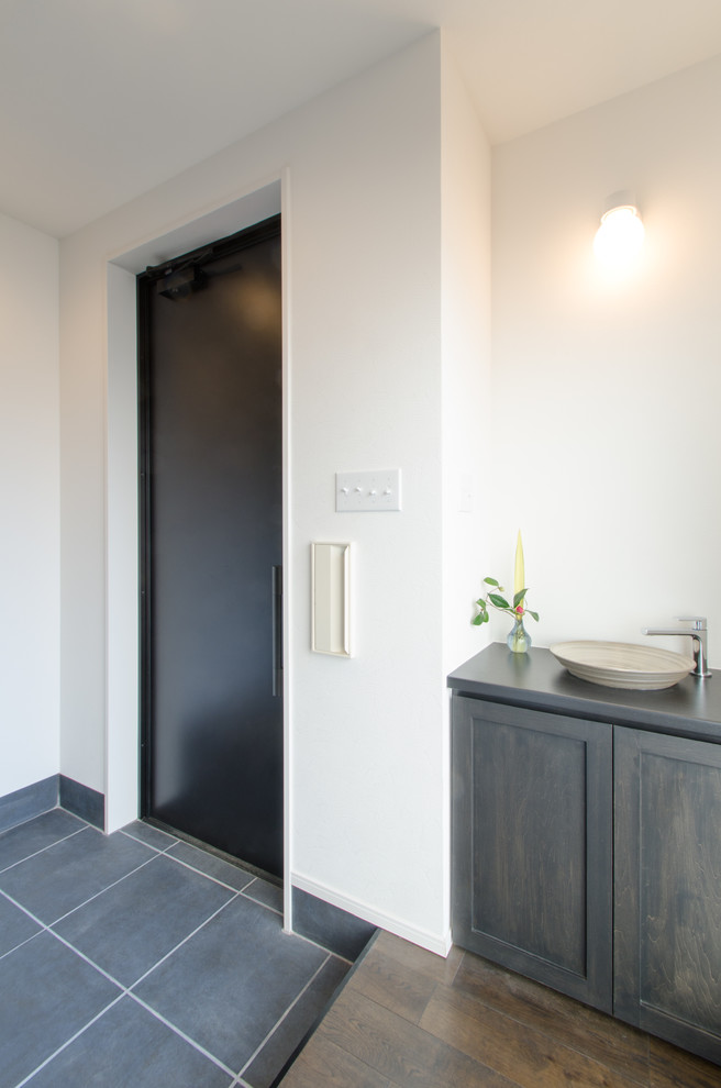 Aménagement d'un vestibule romantique de taille moyenne avec un mur blanc, un sol en ardoise, une porte simple et une porte noire.