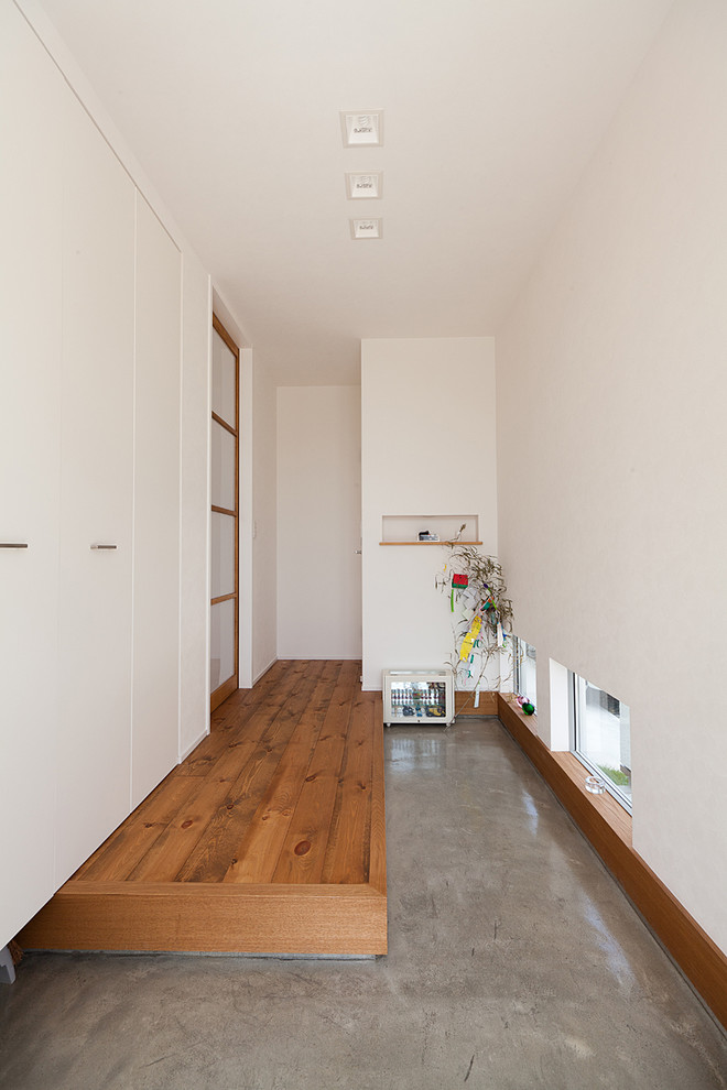 Idee per un ingresso o corridoio con pareti bianche, pavimento in cemento, una porta singola, una porta in legno bruno e pavimento grigio