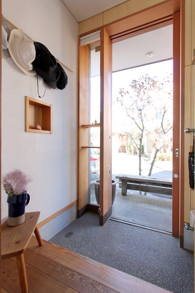 World-inspired entrance in Tokyo Suburbs with white walls, a medium wood front door, grey floors and a pivot front door.