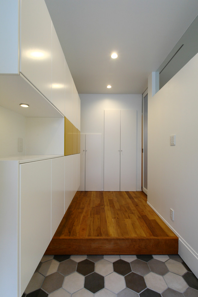 Exemple d'une entrée moderne de taille moyenne avec un couloir, un mur blanc, un sol en bois brun, une porte simple, une porte jaune et un sol marron.