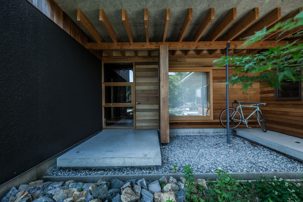 Diseño de entrada contemporánea de tamaño medio con paredes marrones, suelo de cemento, puerta simple, puerta marrón y suelo gris