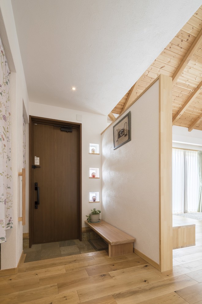 Inspiration pour une entrée minimaliste avec un couloir, un mur blanc, un sol en bois brun, une porte simple, une porte en bois foncé et un sol marron.