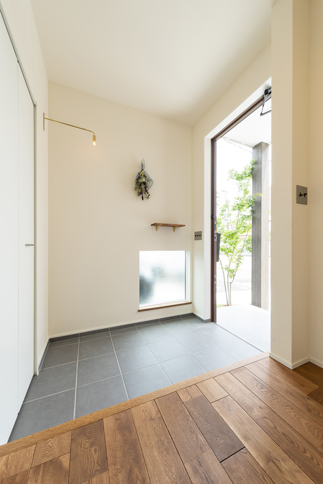 Foto de hall minimalista con paredes blancas, suelo de madera en tonos medios, puerta simple, puerta de madera en tonos medios y suelo marrón