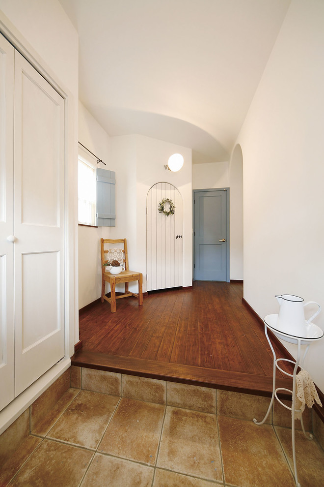 Example of a tuscan beige floor entryway design in Tokyo with white walls