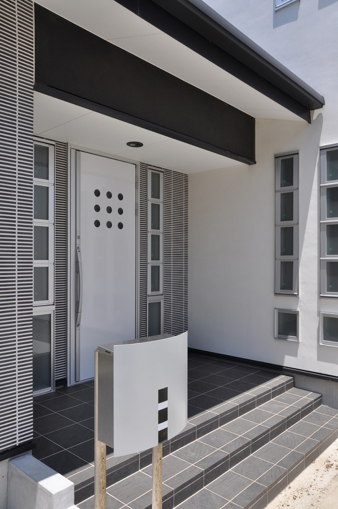Foto de entrada moderna con paredes blancas, suelo de baldosas de porcelana, puerta simple, puerta blanca y suelo negro