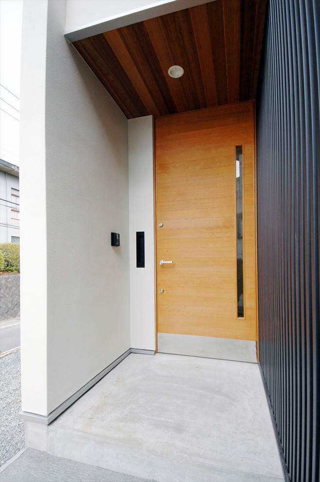 Foto de puerta principal moderna pequeña con suelo de cemento, puerta simple, puerta de madera clara y suelo gris