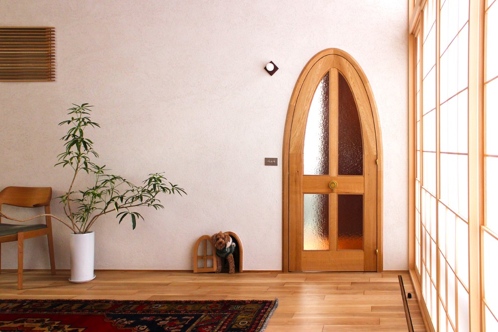 Foto på en orientalisk entré, med vita väggar, ljust trägolv, en enkeldörr, ljus trädörr och beiget golv