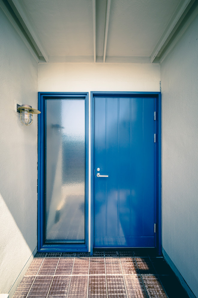 Inredning av en skandinavisk liten ingång och ytterdörr, med klinkergolv i porslin, vita väggar, en enkeldörr, en blå dörr och brunt golv