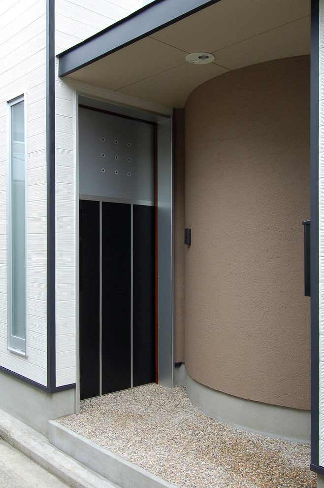 На фото: входная дверь в стиле модернизм с белыми стенами, полом из терраццо, раздвижной входной дверью, черной входной дверью и коричневым полом с