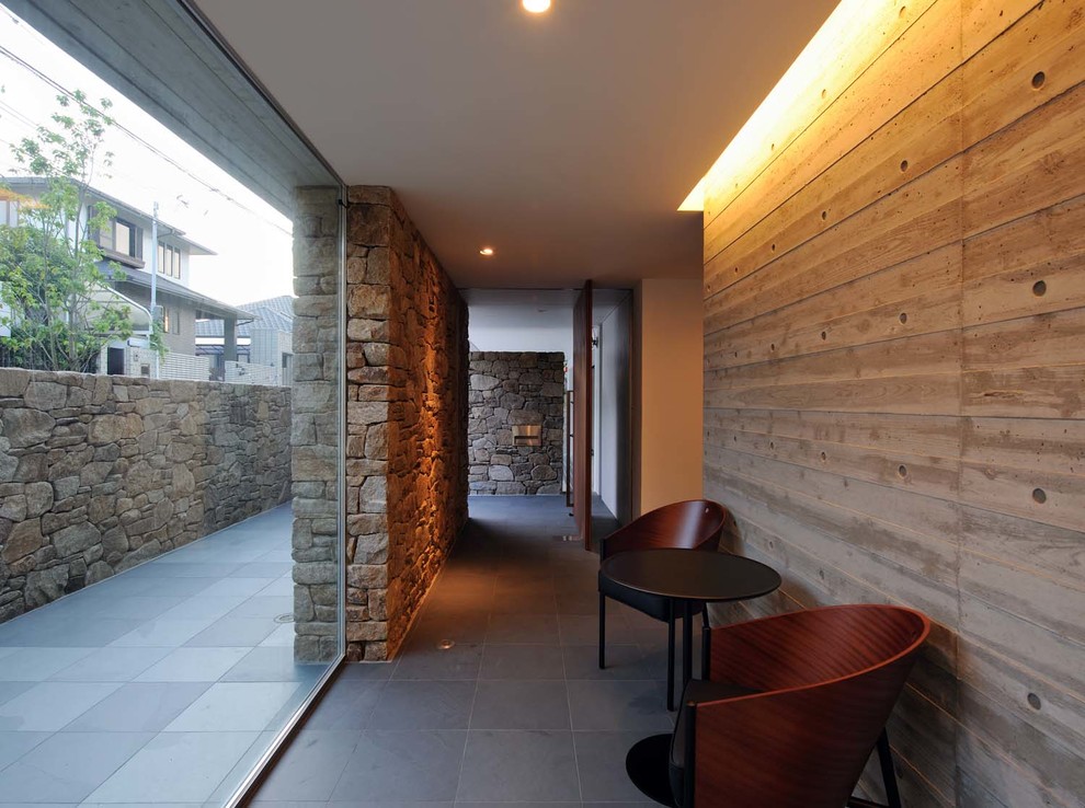 Immagine di un corridoio minimalista con pareti grigie, una porta in legno scuro e una porta a pivot