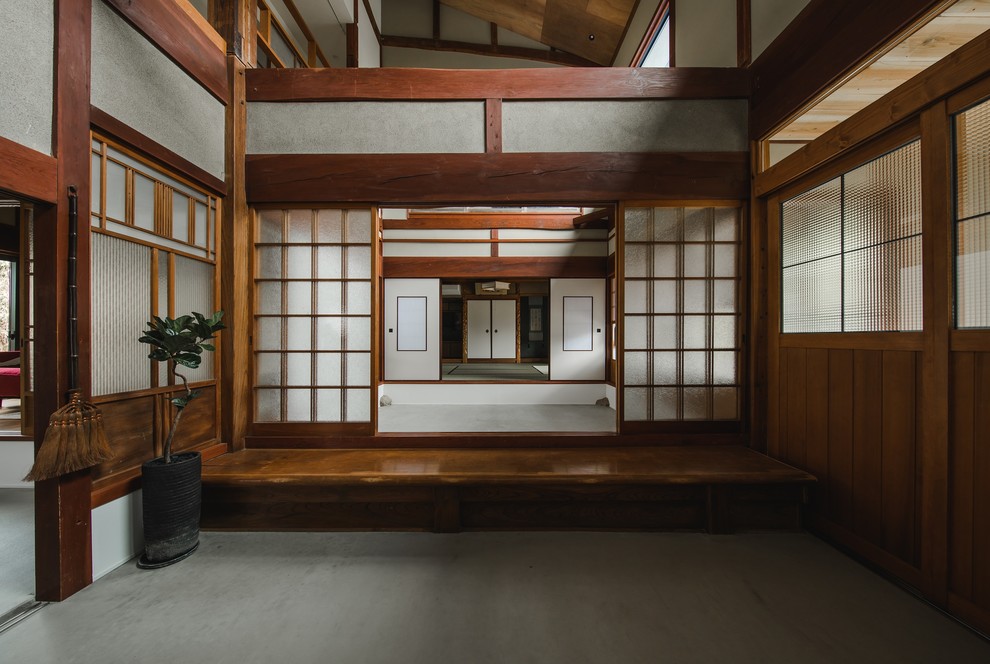 Imagen de hall de estilo zen grande con paredes blancas, suelo de cemento, puerta de madera en tonos medios y suelo gris