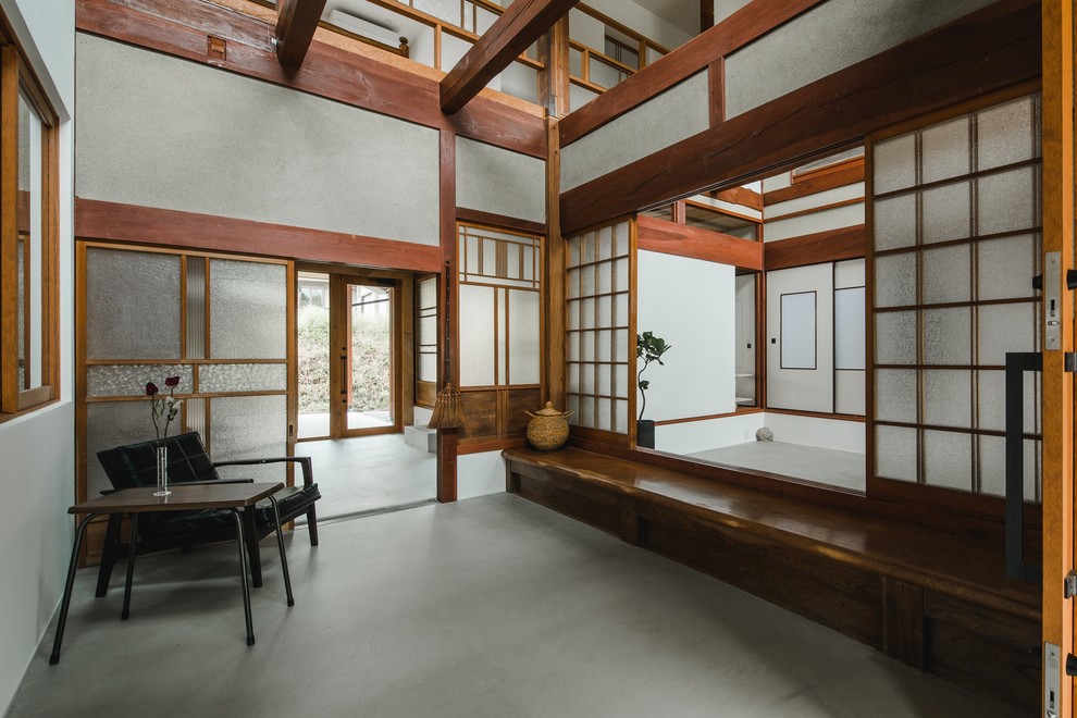 Inspiration pour une très grande entrée asiatique avec un mur gris, sol en béton ciré, un sol gris, un couloir et une porte en bois brun.