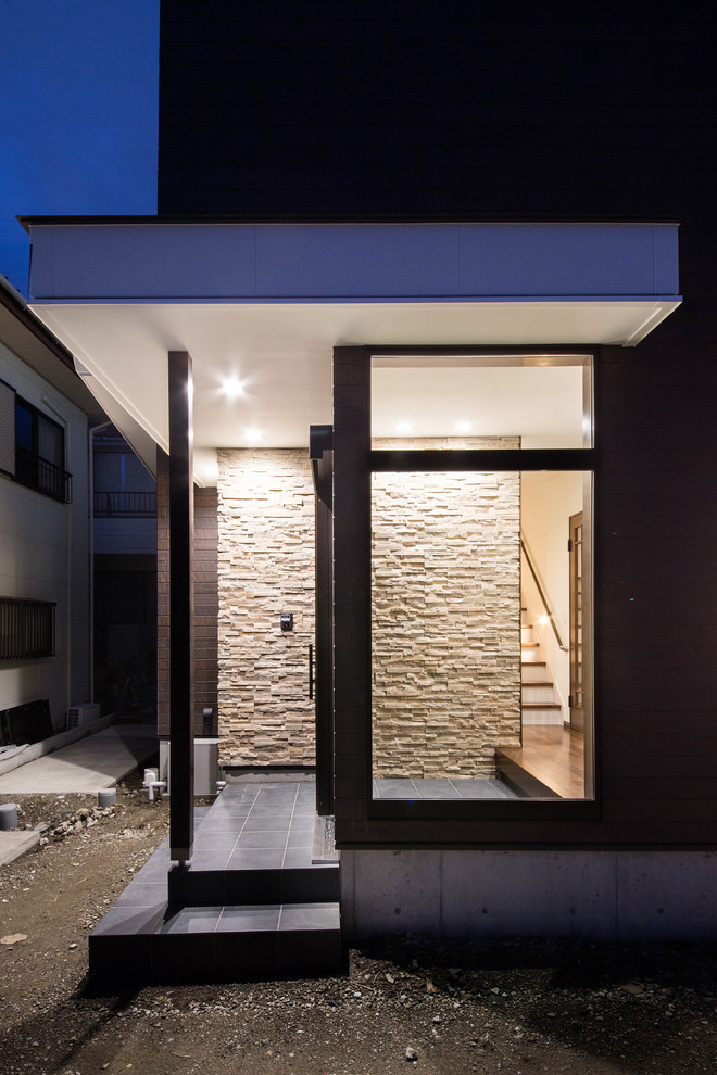 Aménagement d'une entrée asiatique de taille moyenne avec un couloir, un mur beige, sol en granite, une porte coulissante, une porte en bois foncé et un sol noir.