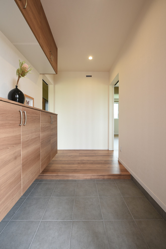 Imagen de hall nórdico de tamaño medio con paredes blancas, suelo de baldosas de cerámica, puerta simple, puerta de madera en tonos medios y suelo gris