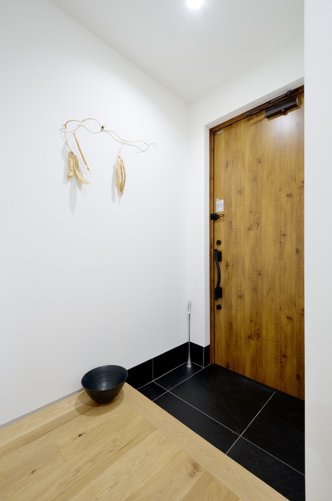 Idéer för en modern hall, med vita väggar, klinkergolv i porslin, en enkeldörr, mellanmörk trädörr och svart golv