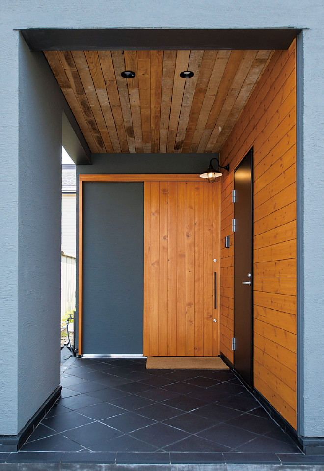 Стильный дизайн: прихожая в восточном стиле с серыми стенами, полом из керамогранита и входной дверью из дерева среднего тона - последний тренд