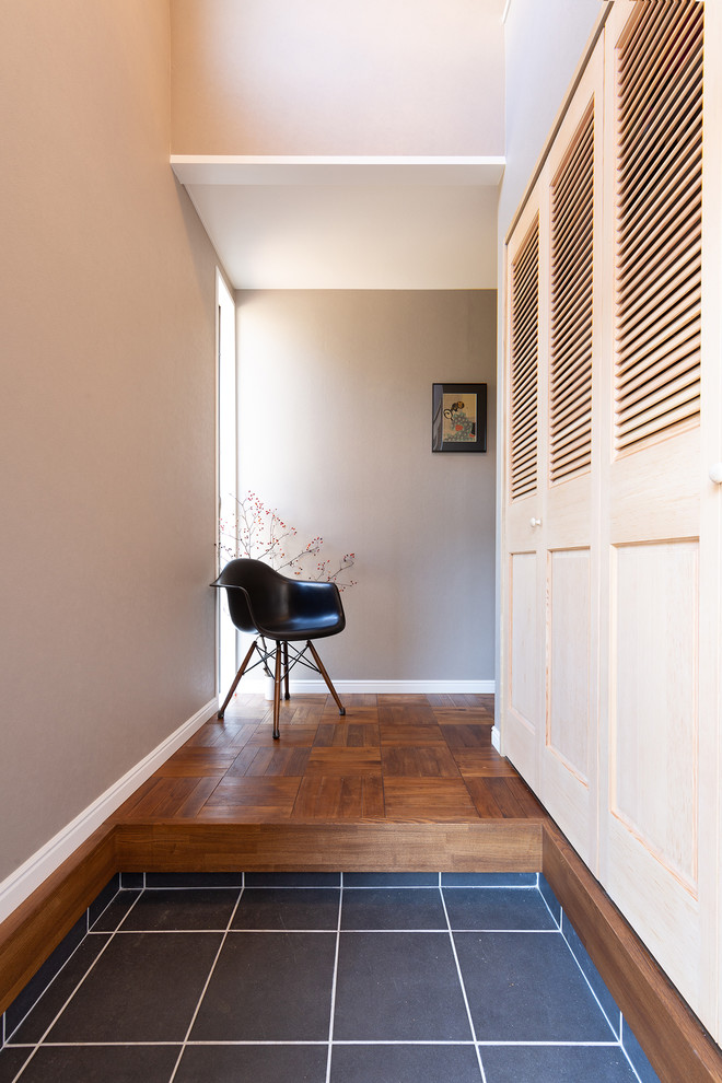 Esempio di un corridoio con pareti grigie, pavimento in legno massello medio, una porta singola e pavimento marrone