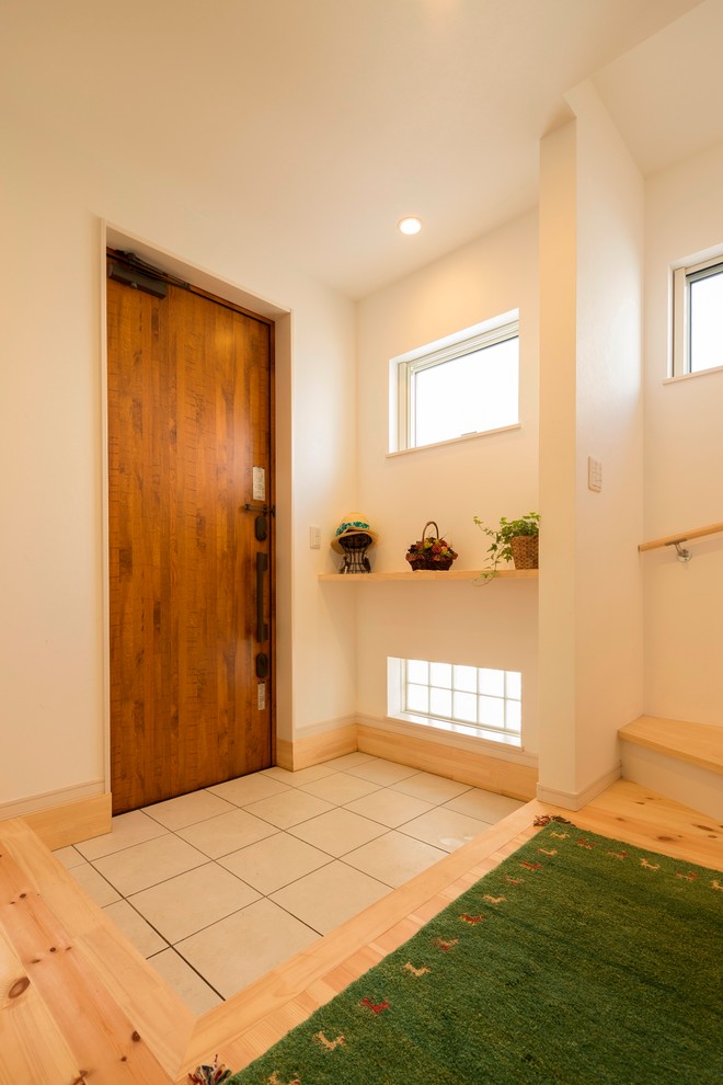 他の地域にあるミッドセンチュリースタイルのおしゃれな玄関ホール (白い壁、濃色木目調のドア、グレーの床) の写真