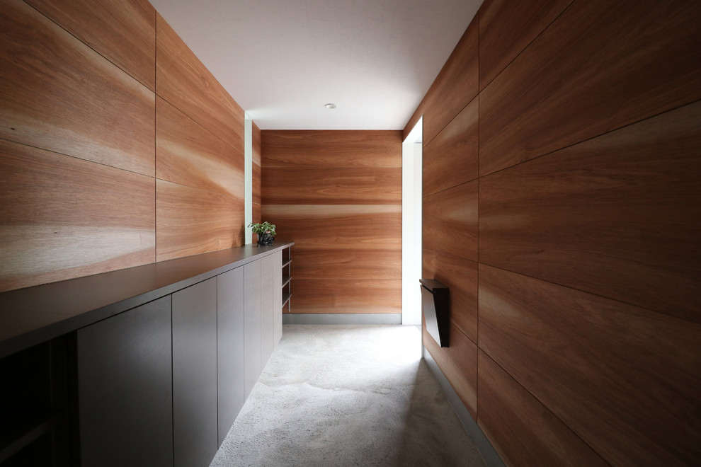 Свежая идея для дизайна: прихожая в стиле модернизм с коричневыми стенами, бетонным полом, раздвижной входной дверью и серым полом - отличное фото интерьера