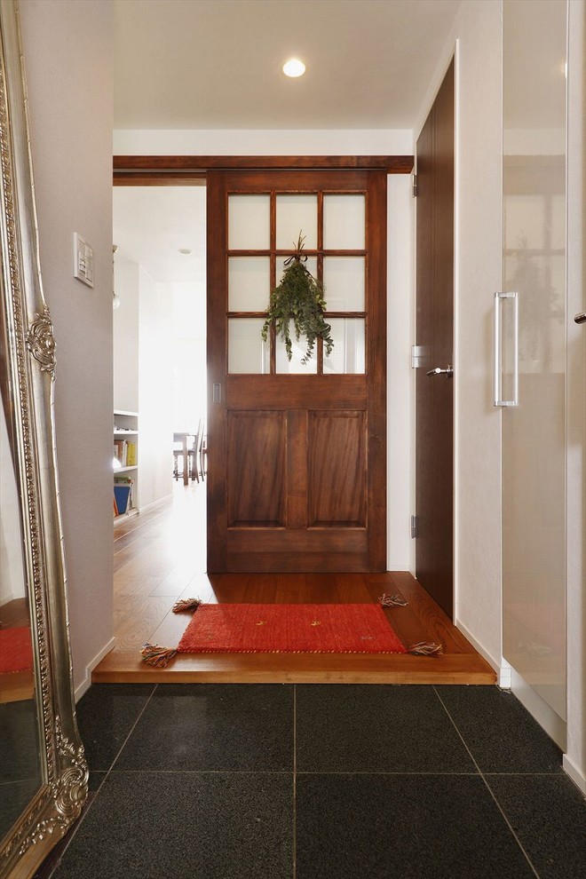 カントリー風のおしゃれな玄関ホール (白い壁、木目調のドア) の写真