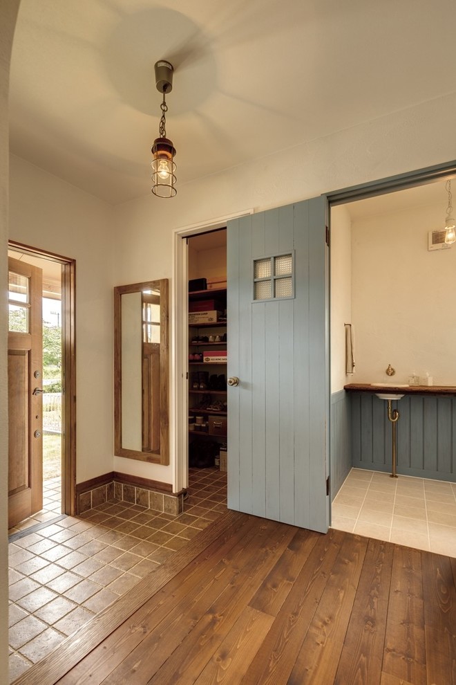 Источник вдохновения для домашнего уюта: прихожая в стиле кантри с белыми стенами, полом из терракотовой плитки, одностворчатой входной дверью, входной дверью из дерева среднего тона и коричневым полом