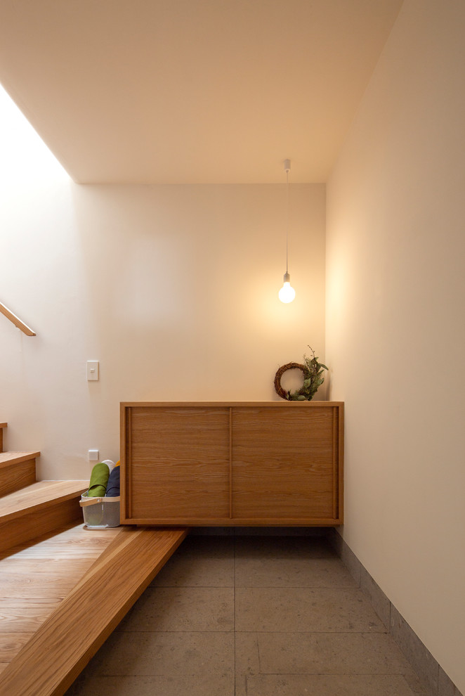 Idéer för en asiatisk entré, med en enkeldörr, vita väggar och grått golv