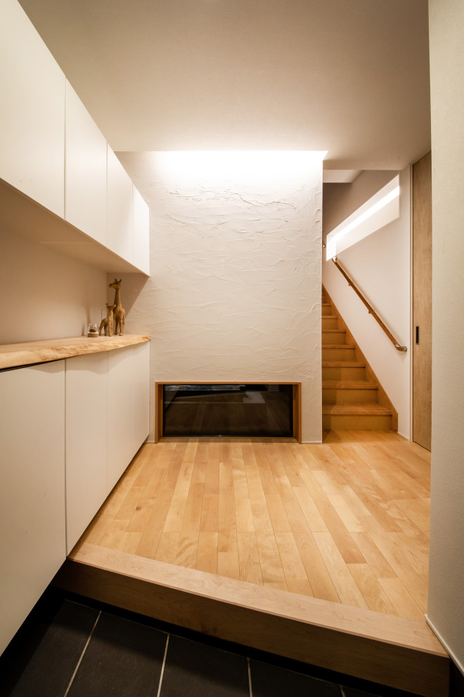 Foto di un corridoio minimalista di medie dimensioni con pareti bianche, pavimento in legno massello medio, una porta scorrevole, una porta in legno bruno, pavimento beige e soffitto in carta da parati