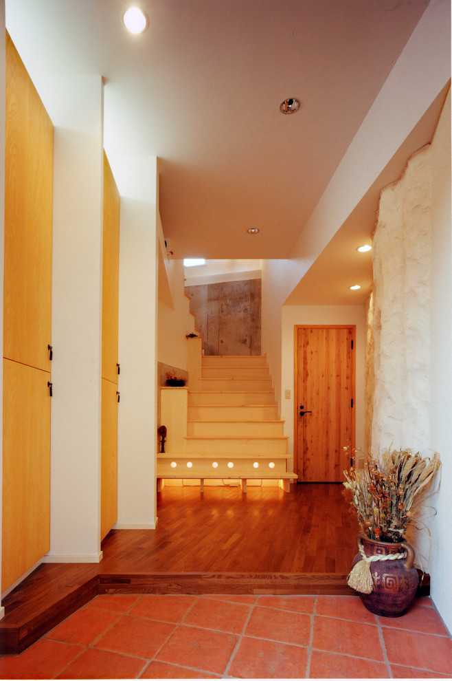 他の地域にある地中海スタイルのおしゃれな玄関 (白い壁、テラコッタタイルの床、オレンジの床) の写真
