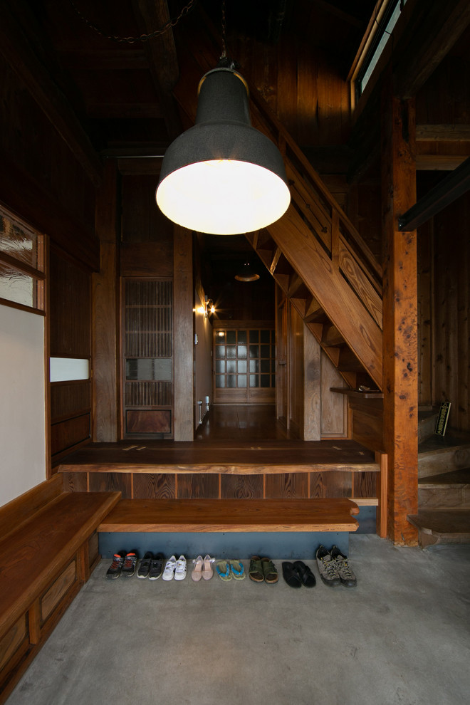 Modelo de hall actual de tamaño medio con paredes blancas, puerta de madera en tonos medios, vigas vistas, suelo de cemento y suelo gris