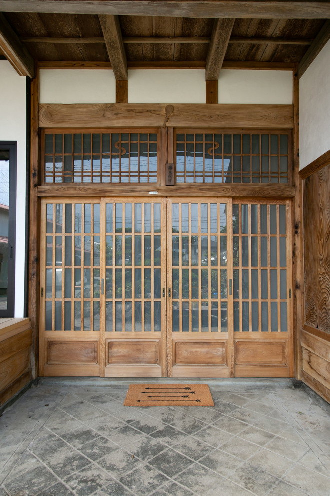Diseño de puerta principal actual de tamaño medio con paredes blancas, suelo de madera en tonos medios, puerta corredera, puerta de madera en tonos medios, suelo beige y vigas vistas