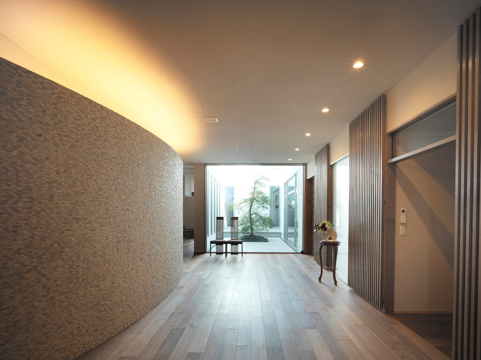Idées déco pour une très grande entrée contemporaine avec un couloir, un mur beige, un sol en bois brun, une porte simple, une porte en bois foncé et un sol marron.