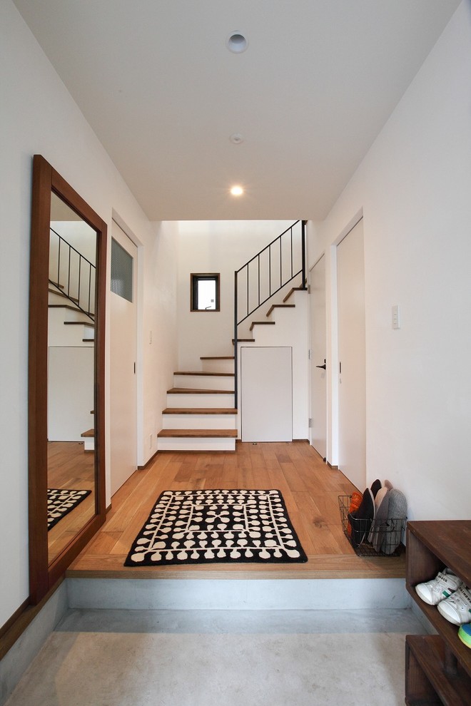 Exempel på en modern entré, med vita väggar, betonggolv och grått golv