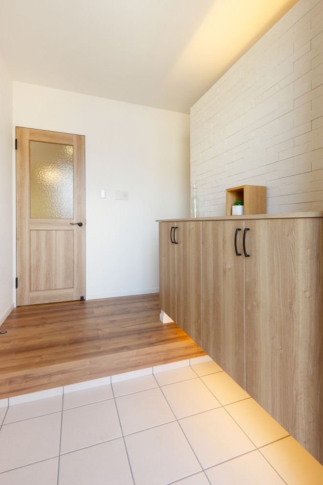 Imagen de entrada nórdica con paredes blancas, suelo de madera en tonos medios y suelo marrón