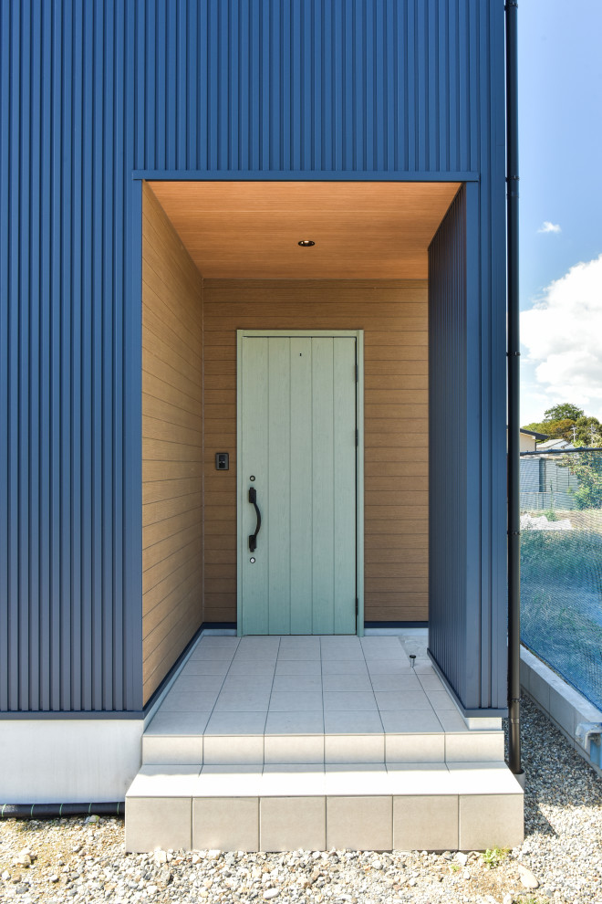 Modelo de puerta principal marinera con paredes azules, suelo de madera pintada, puerta simple, puerta verde, suelo blanco y machihembrado