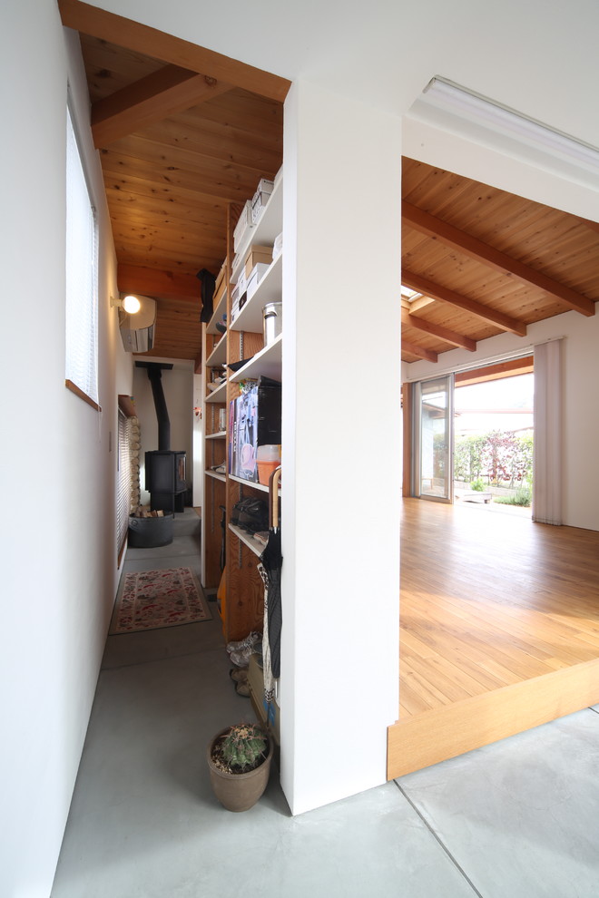 На фото: прихожая в стиле лофт с белыми стенами, бетонным полом, раздвижной входной дверью и серым полом