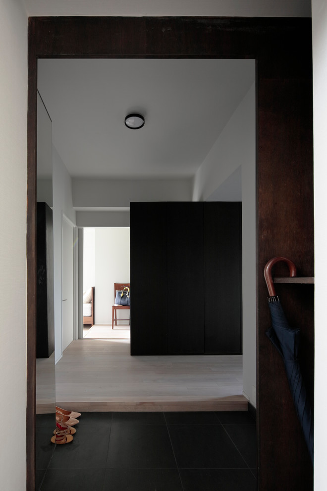 Пример оригинального дизайна: узкая прихожая в стиле модернизм с белыми стенами, полом из фанеры, одностворчатой входной дверью и бежевым полом