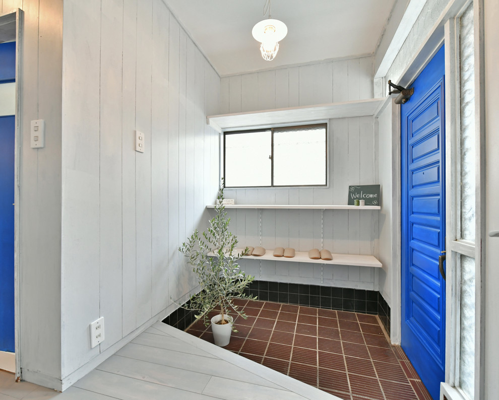 他の地域にあるアジアンスタイルのおしゃれな玄関 (グレーの壁、青いドア、茶色い床) の写真