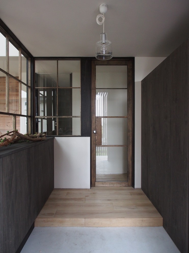 Inspiration for an industrial concrete floor entry hall remodel in Other with brown walls