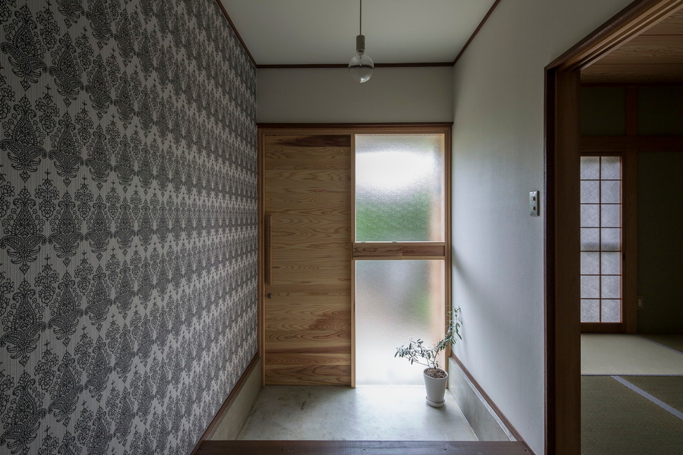 Cette image montre une porte d'entrée asiatique de taille moyenne avec une porte en bois clair, un mur multicolore, sol en béton ciré, un sol gris et une porte coulissante.