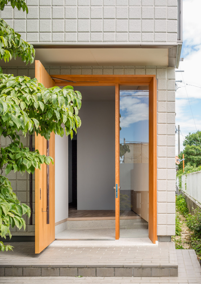 Cette image montre une porte d'entrée asiatique de taille moyenne avec un mur blanc, une porte simple, une porte en bois brun et un sol blanc.