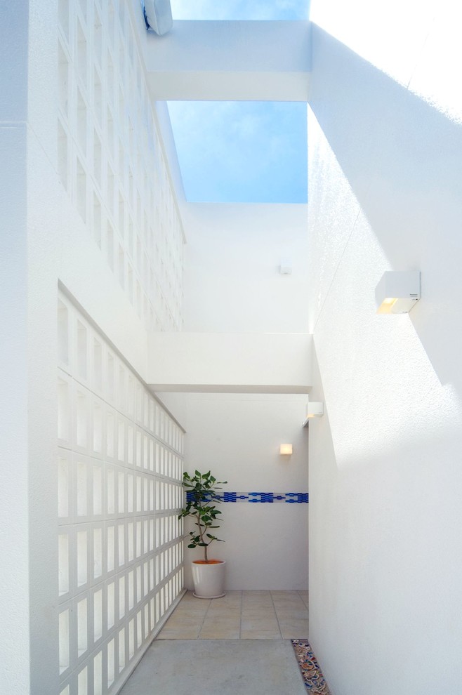他の地域にある地中海スタイルのおしゃれな玄関 (白い壁、磁器タイルの床) の写真