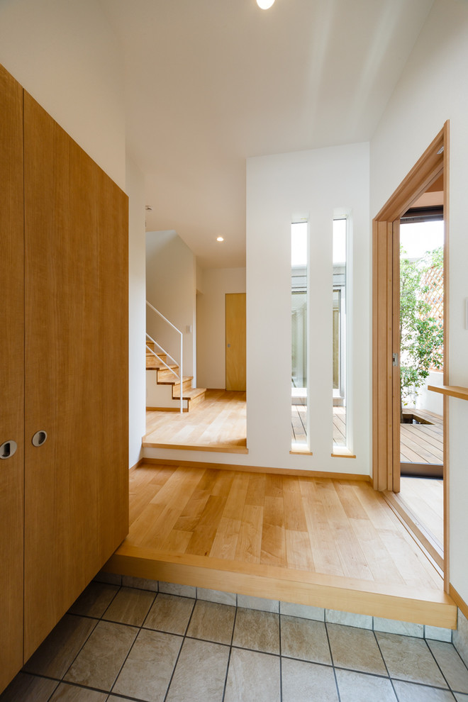 Ejemplo de hall minimalista con paredes blancas, suelo de madera en tonos medios, puerta simple, puerta de madera en tonos medios y suelo beige